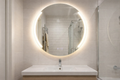 Bathroom with round illuminated mirror above a sink