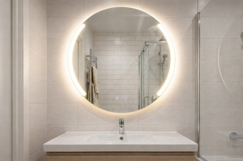 Bathroom with round illuminated mirror above a sink